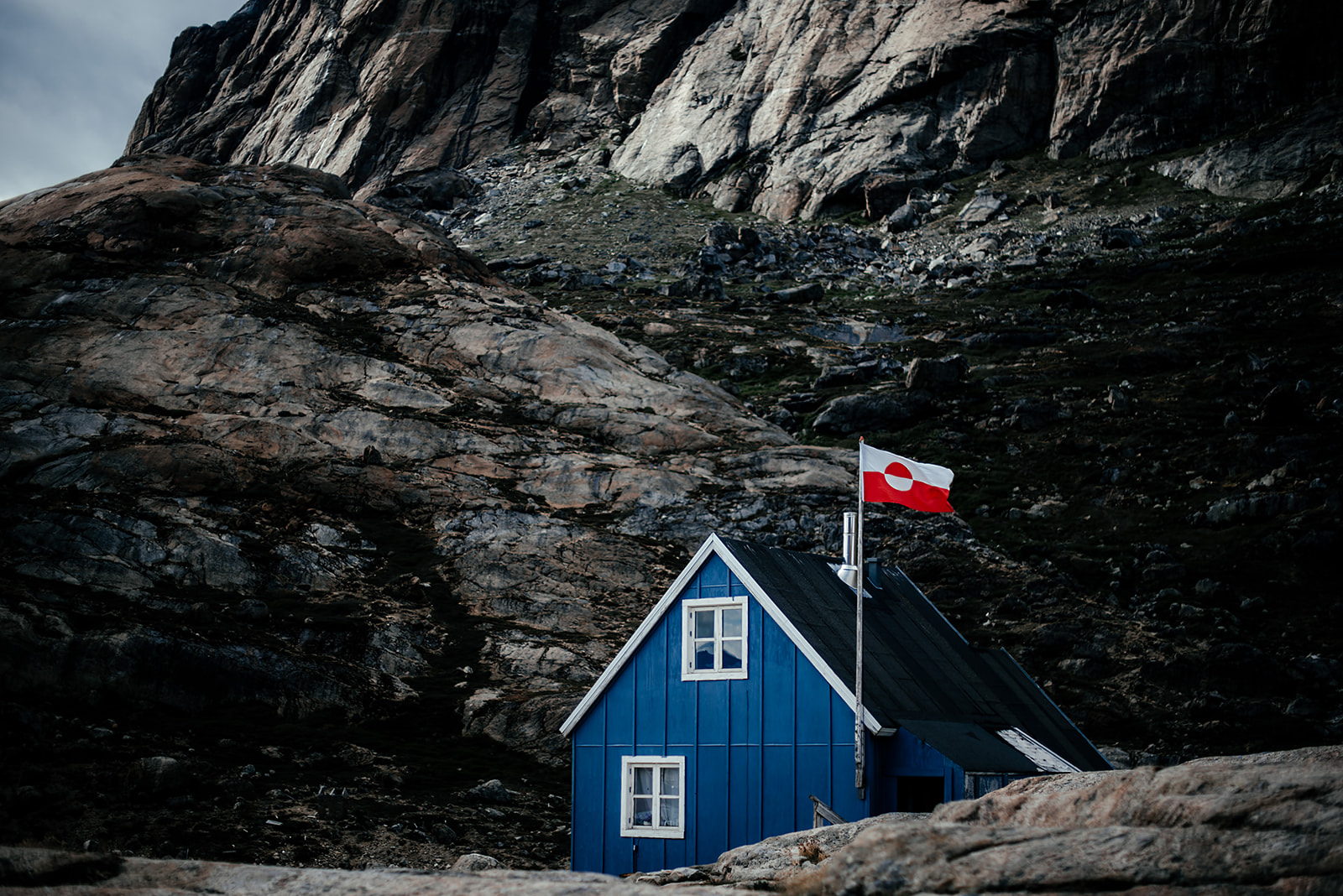 blue wooden house with flag of Greenland