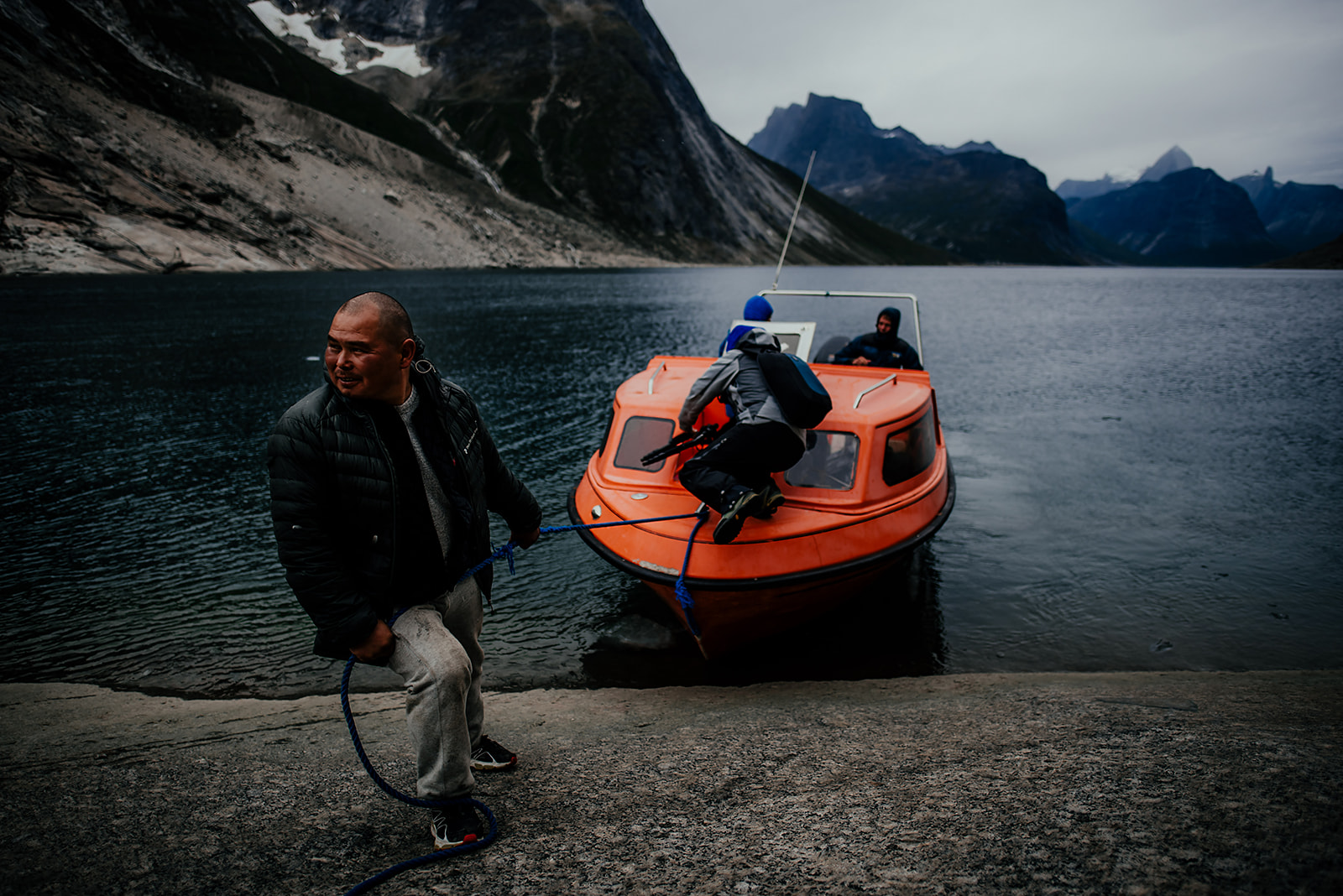 captain holding small orange boat near shore on Greenland