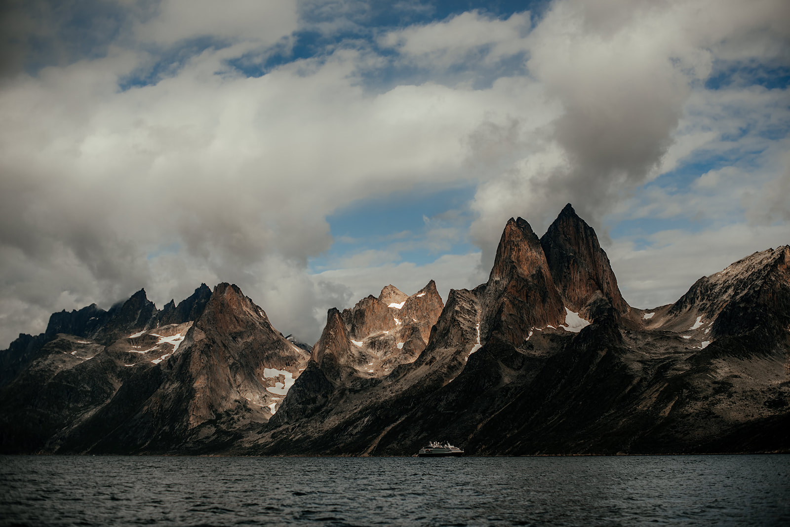 cruise ship in front of majestic mountain range on Greenland