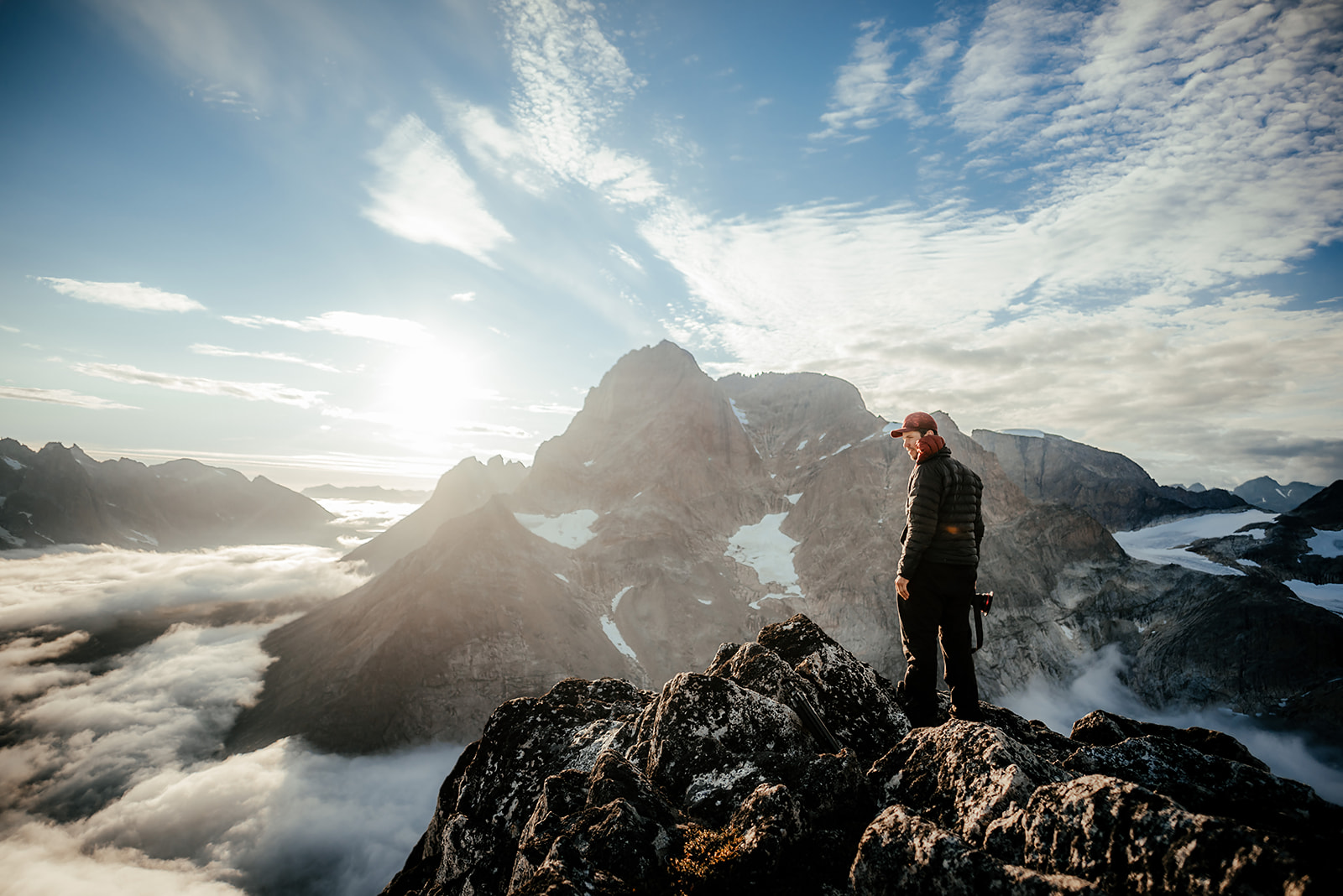 traveler standing at top of peak on Greenland
