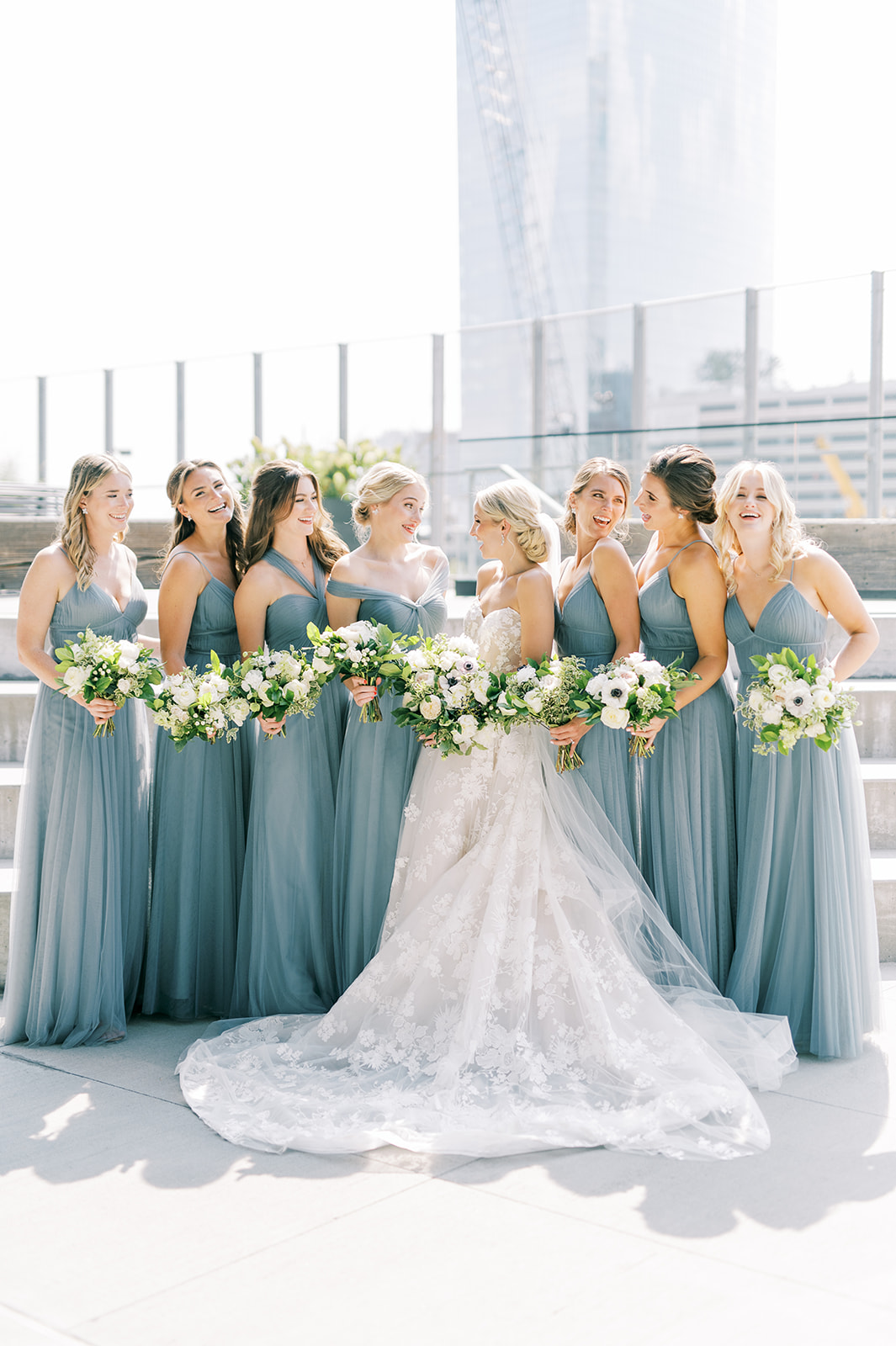 bridesmaids huddle and laugh in pale blue dresses for Secret Urban Garden Wedding at Philadelphia’s Fitler Club