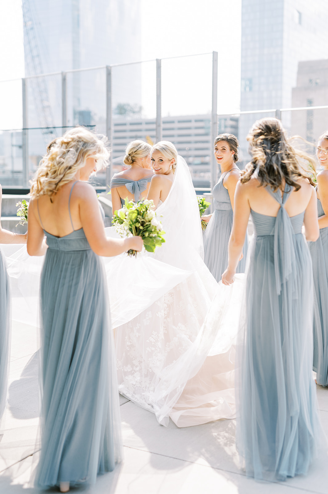 sunny bride walking with bridesmaids in pale blue for Secret Urban Garden Wedding at Philadelphia’s Fitler Club