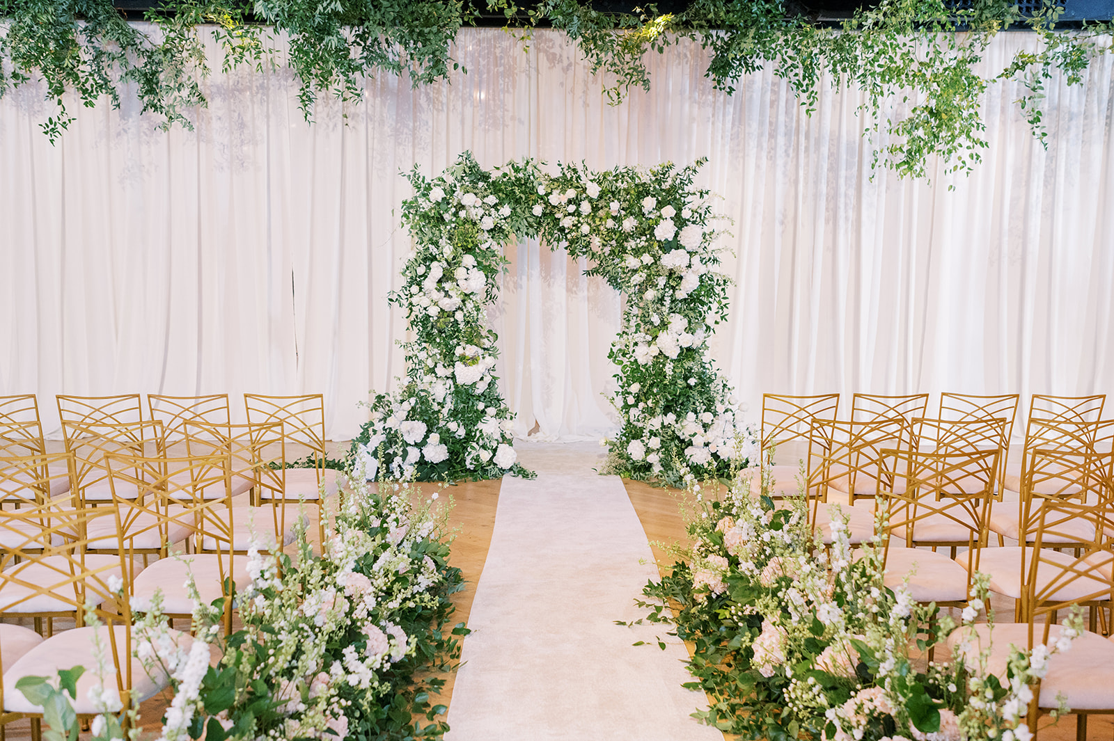 white floral adorned aisle and arch at industrial Secret Urban Garden Wedding at Philadelphia’s Fitler Club
