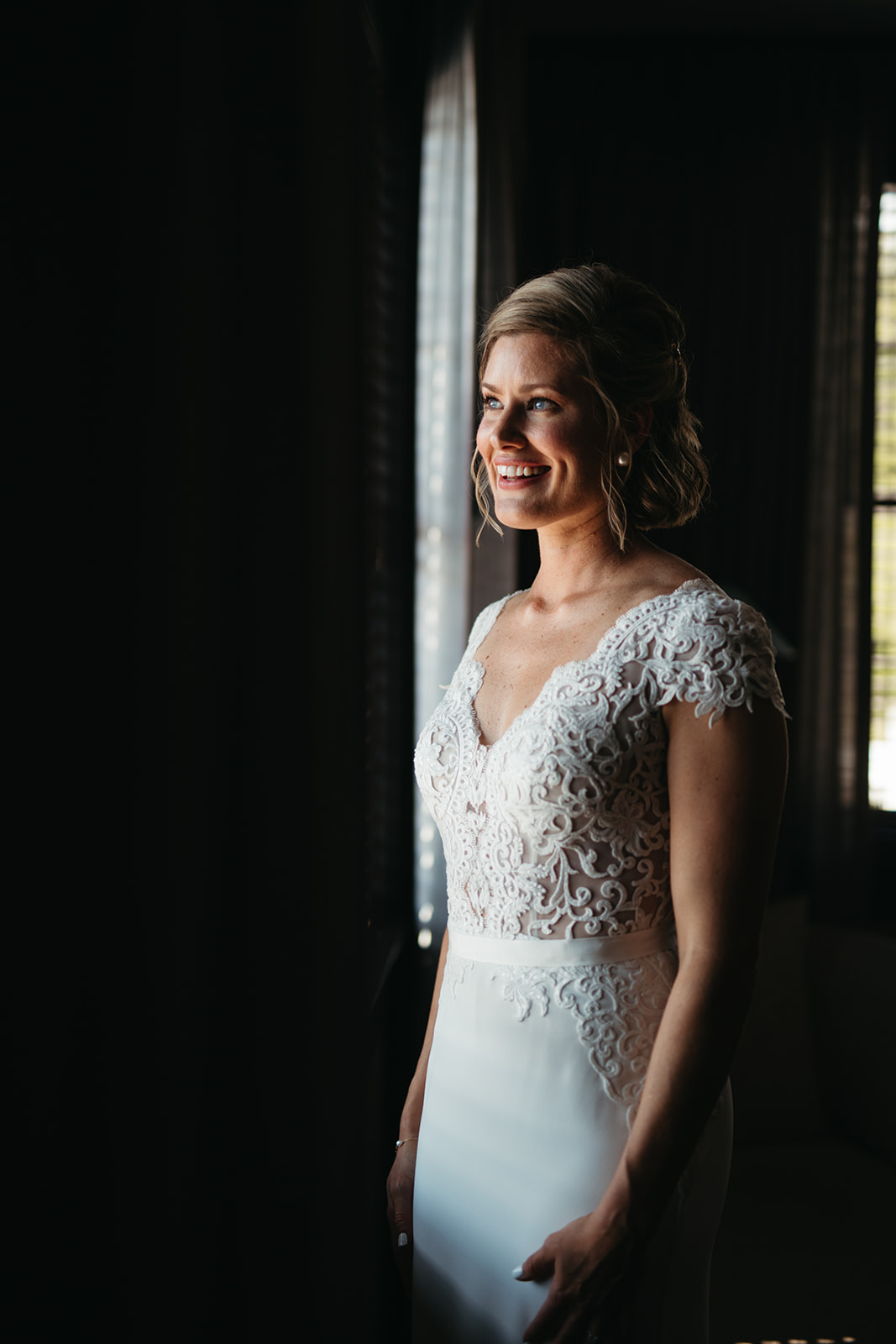 Bride in white dress standing by the window
