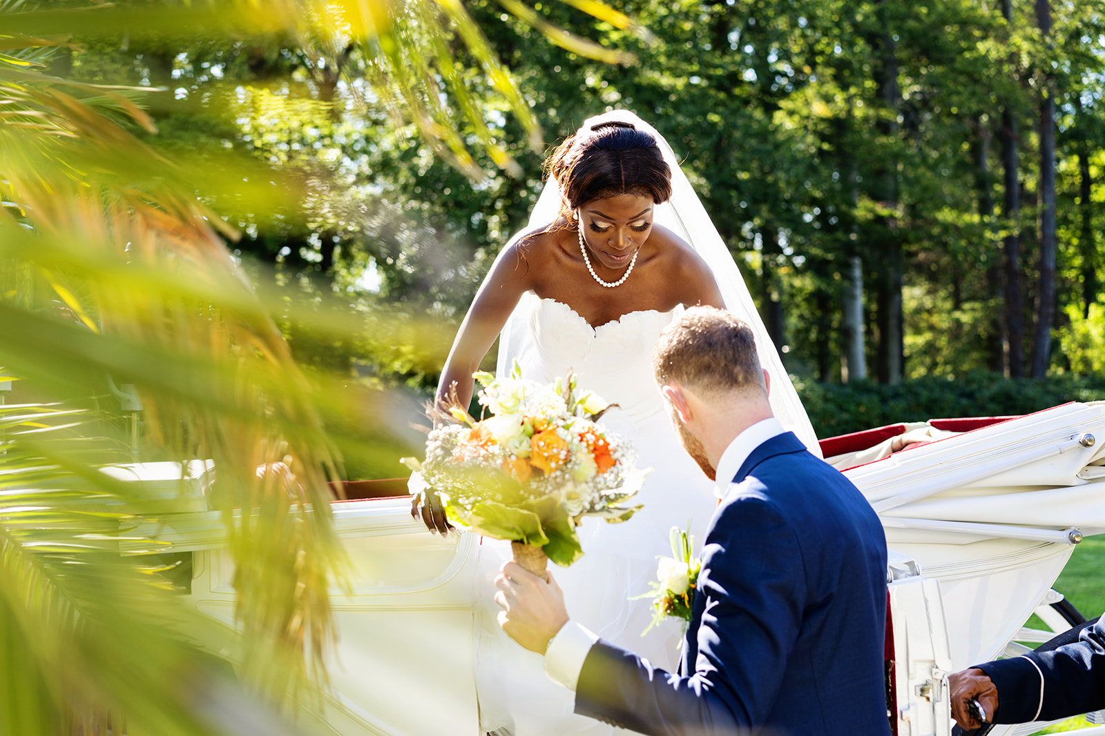 Bruidegom helpt bruid uit de trouwkoets - Trouwen bij Landgoed Sandenburg in Utrecht