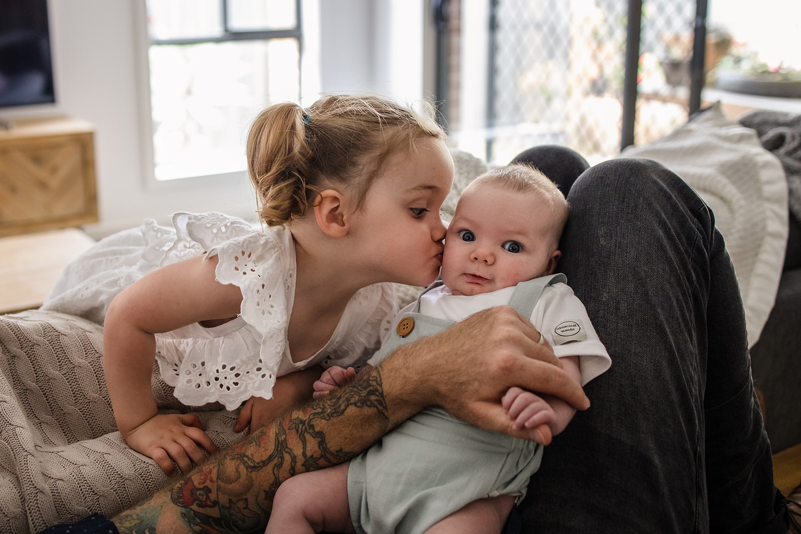 newborn baby being kissed by toddler sister