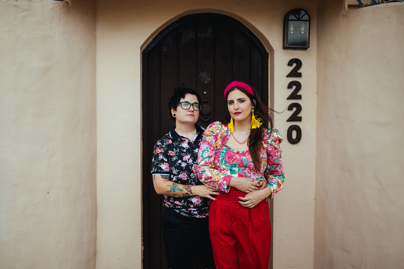 LGBTQ couple in colorful outfits stands in front of an arched doorway in San Juan Puerto Rico.