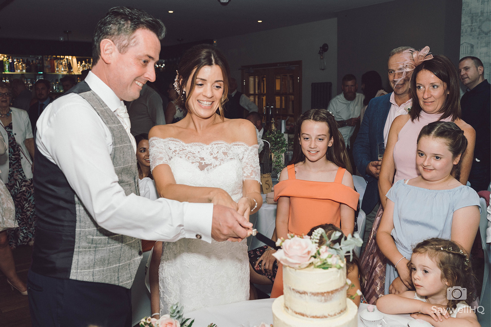 The Chequers Inn Wedding Photography - the bride and groom cutting the wedding cake in front of the wedding guests