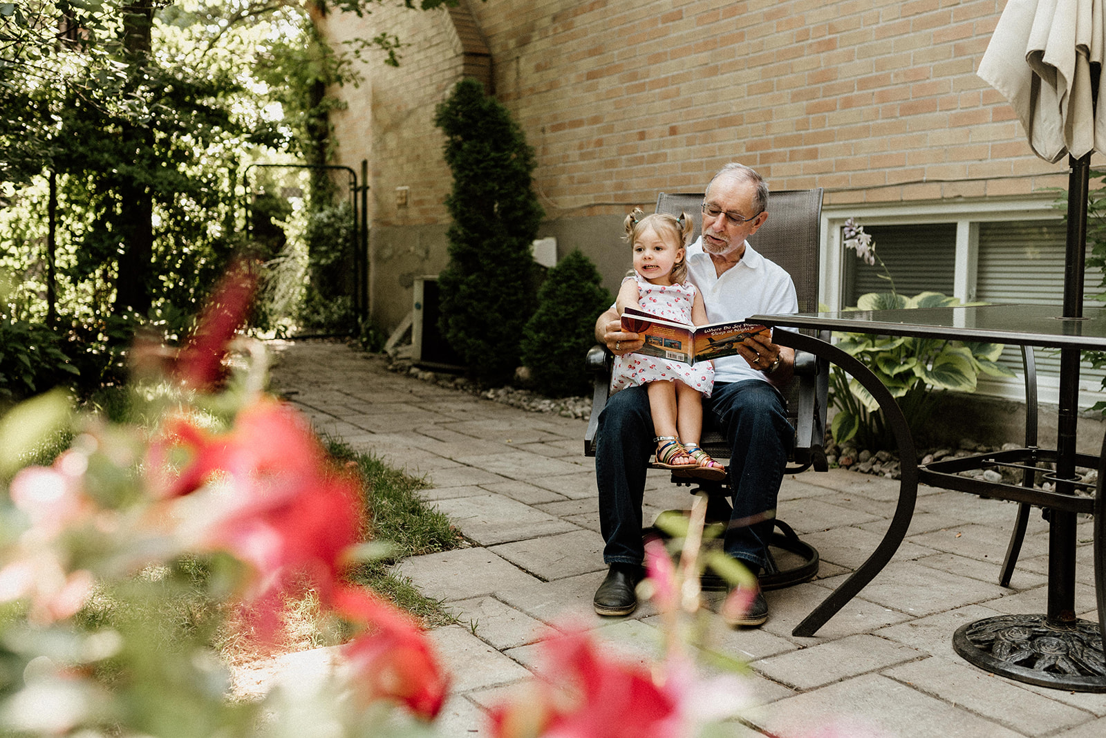 Grandpapa reading story book for her granddaughter in the backyard