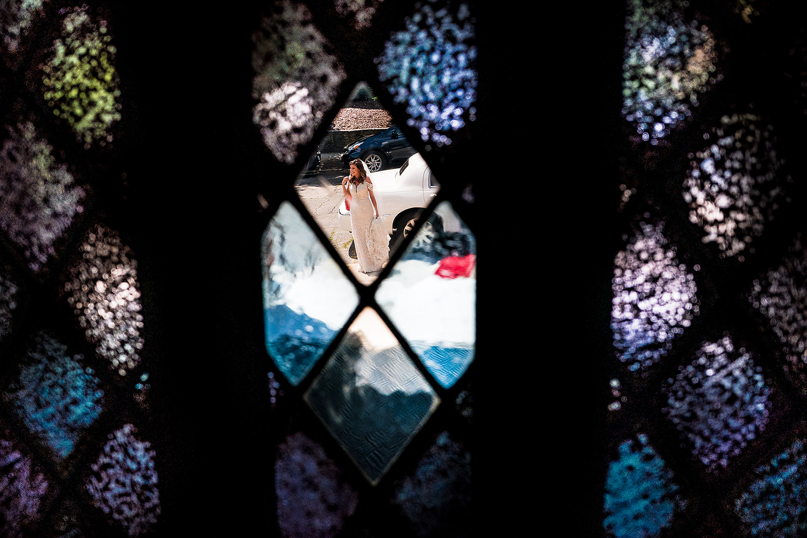 Bride arriving at St. Sebastian’s Church looking through stain glass window
