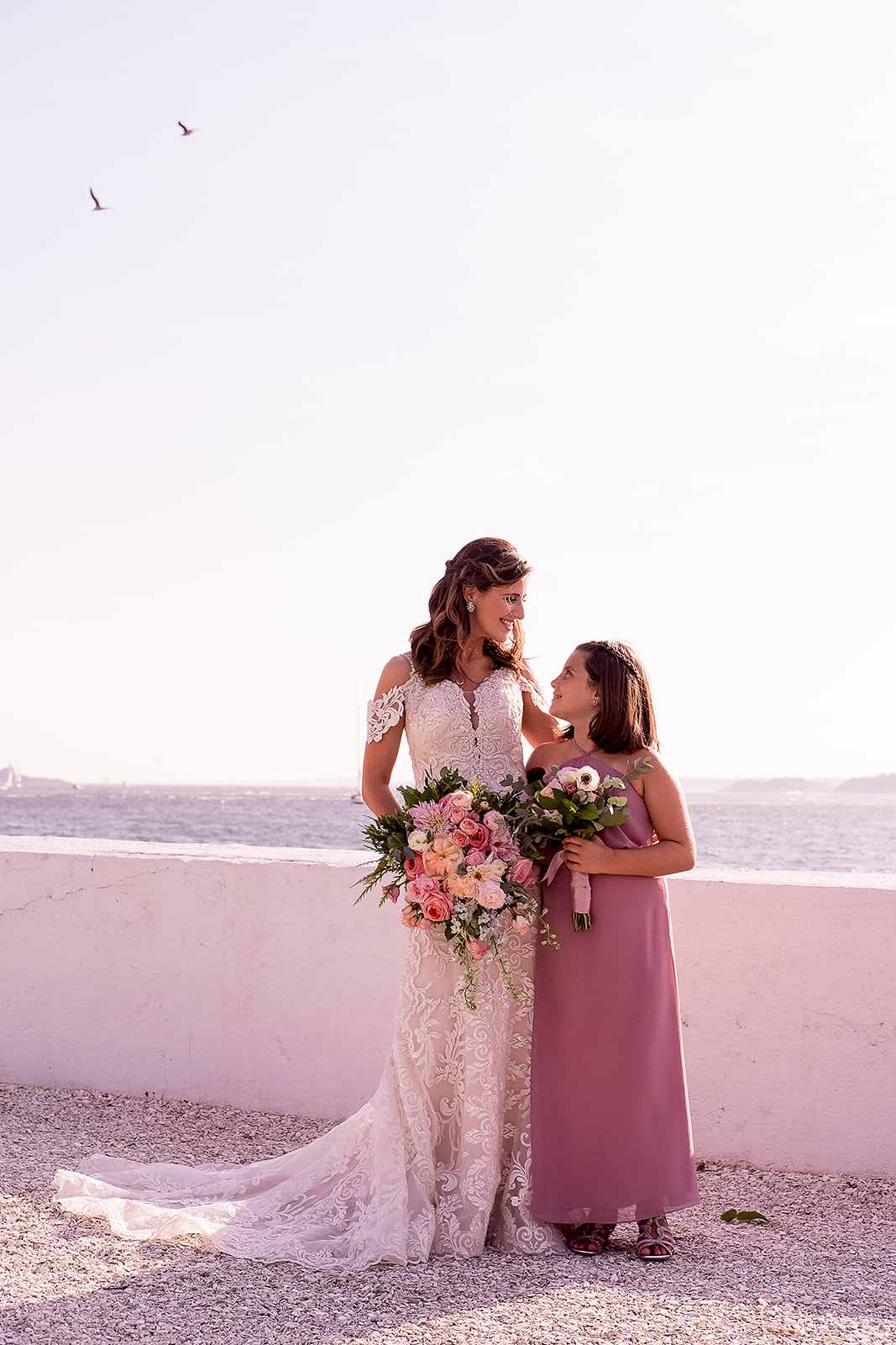 bride and flower girl portrait by the water at Belle Mer