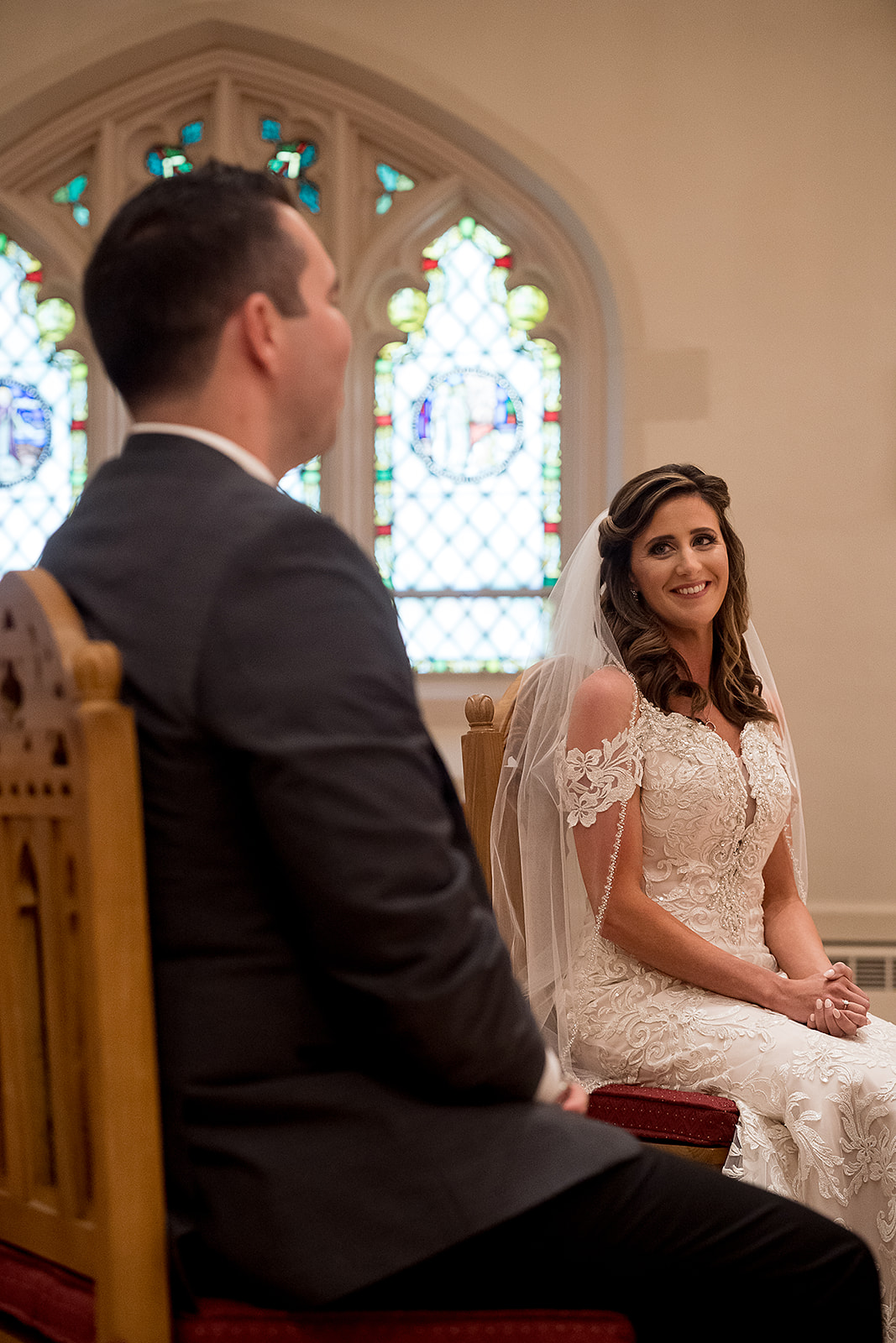 bride looks at groom during Catholic wedding ceremony at St. Sebastian’s Church in Providence Rhode Island
