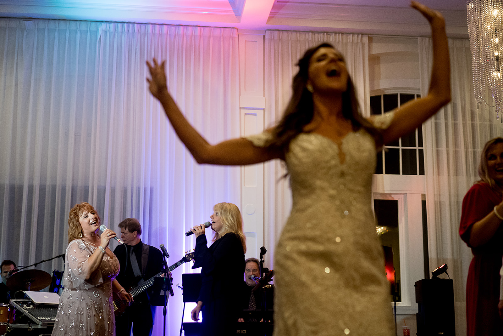 brides mother sings with the live band while bride dances at belle mer wedding reception 