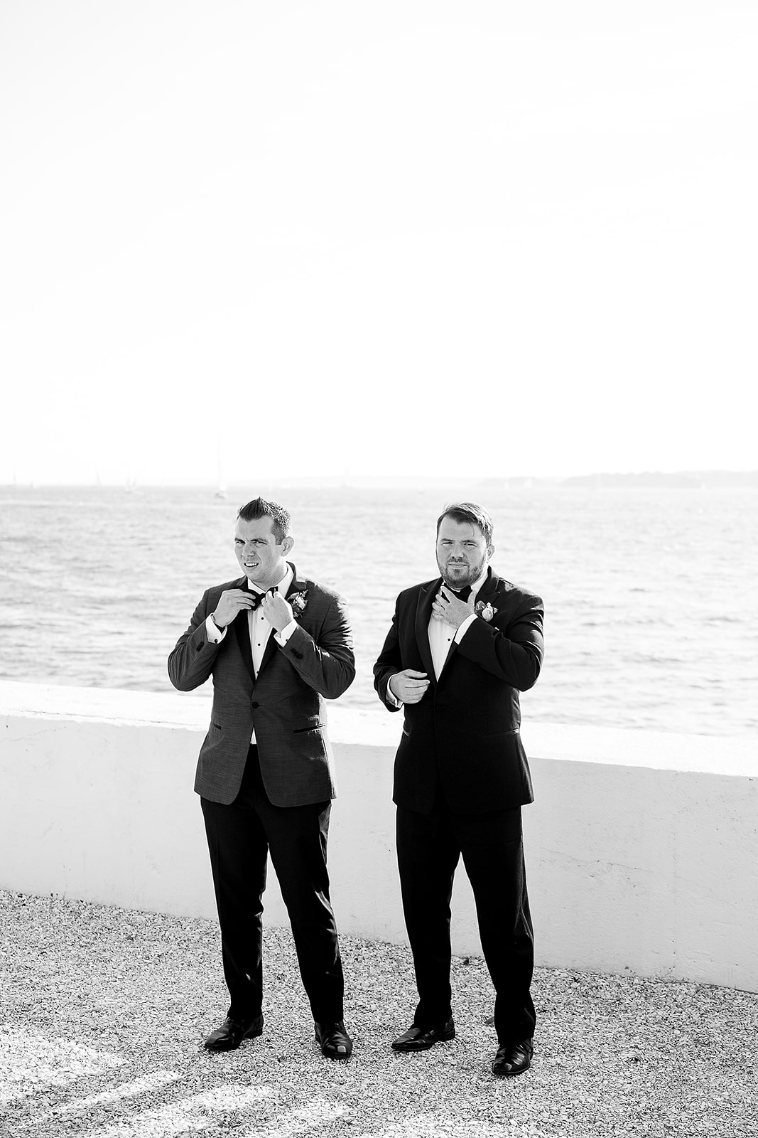 groom and brother both adjust bow tie at the same time during family photos at belle mer