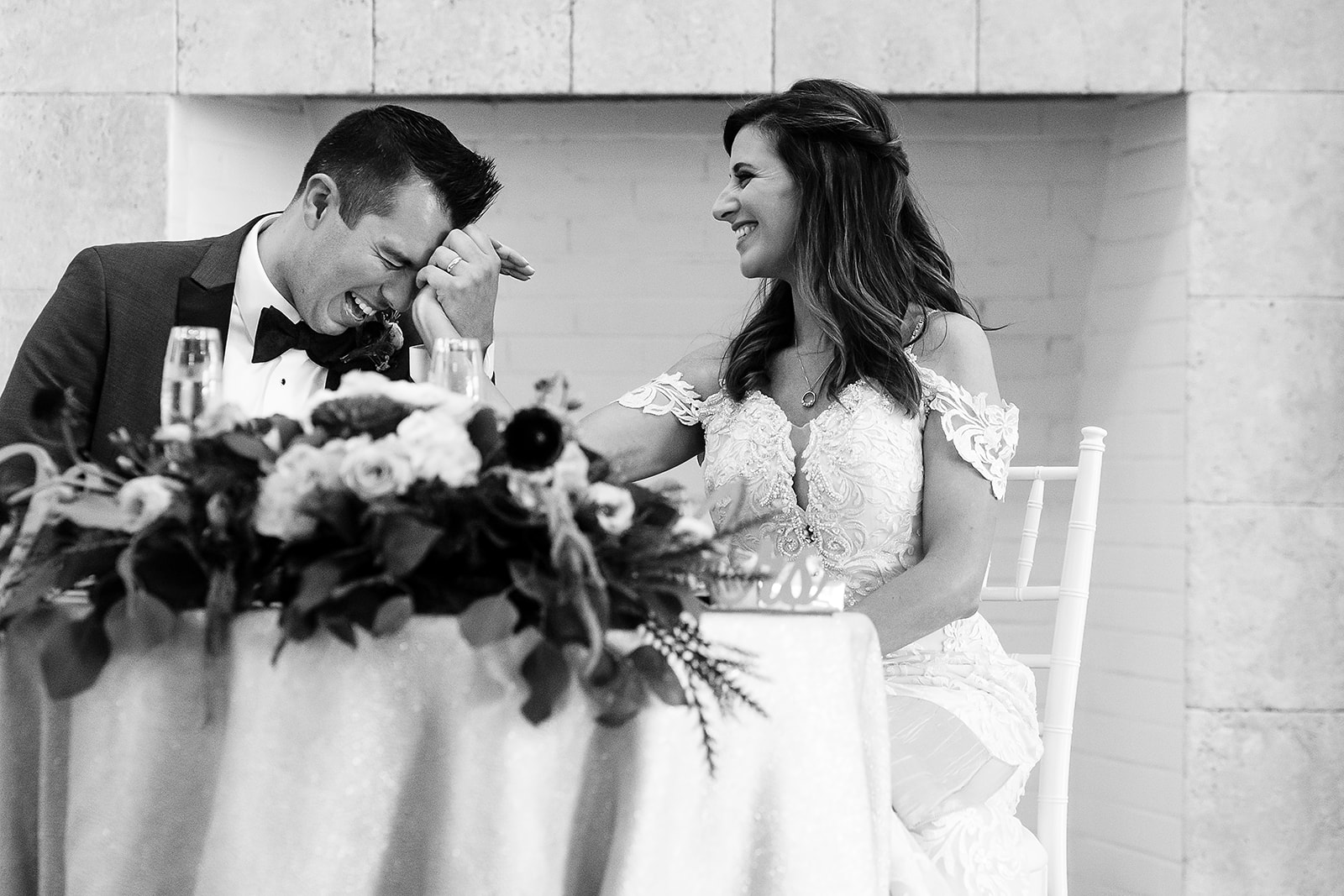 groom laughs while holding brides hand at belle mer wedding reception 