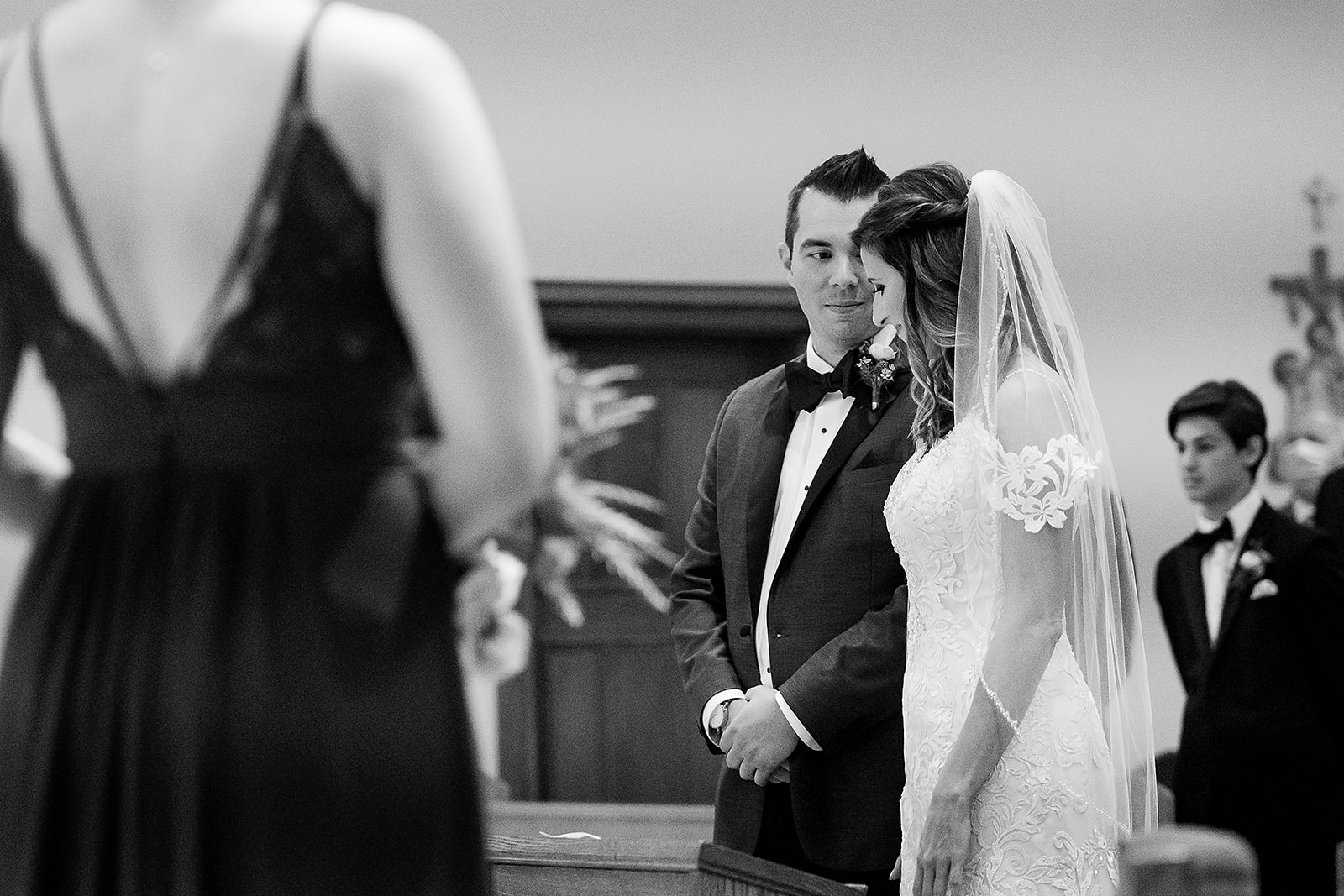groom looks at bride during Catholic wedding ceremony at St. Sebastian’s Church in Providence Rhode Island