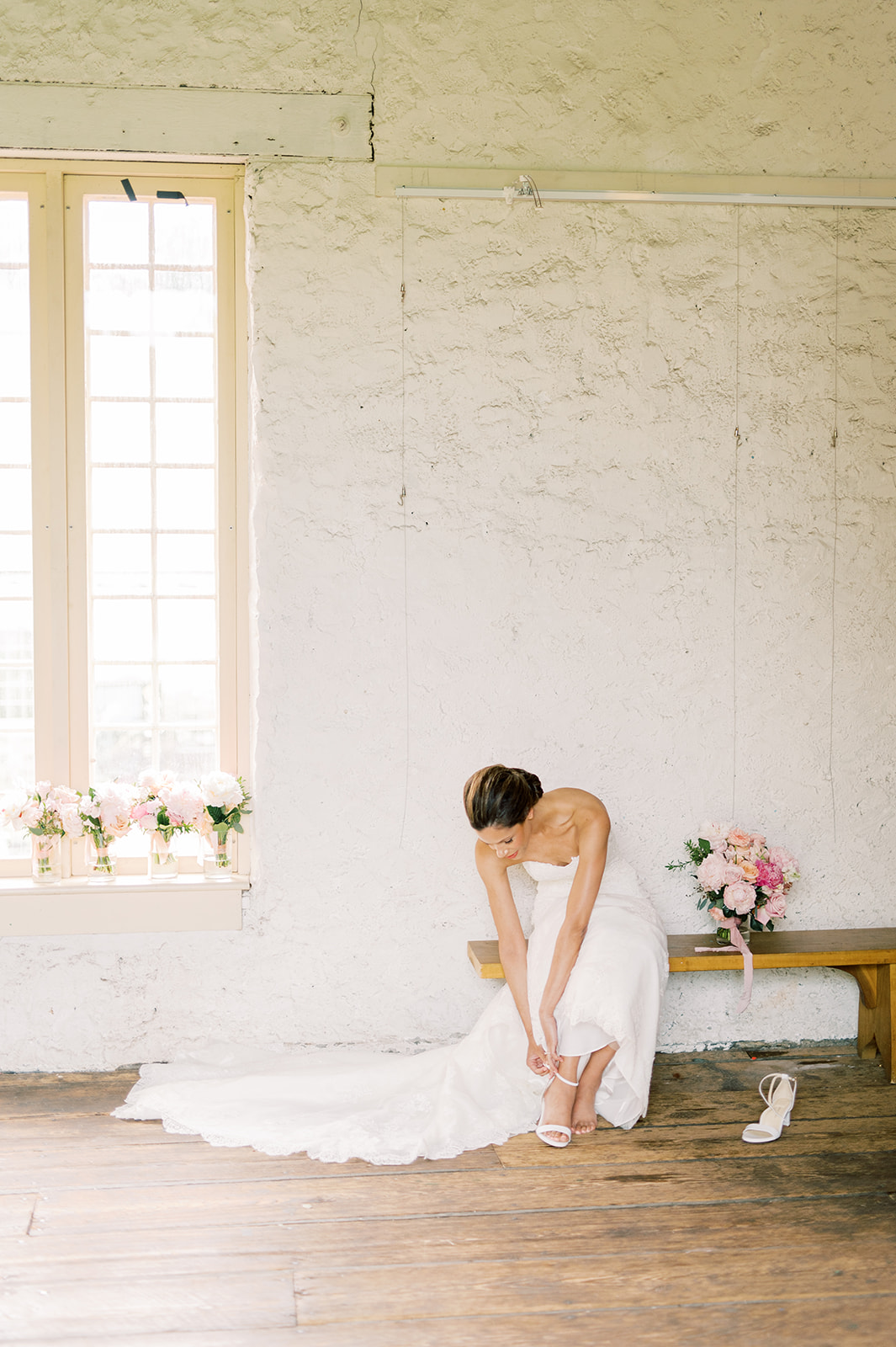 bride puts on her shoes in rustic room for parisian inspired spring Bartram's Garden wedding