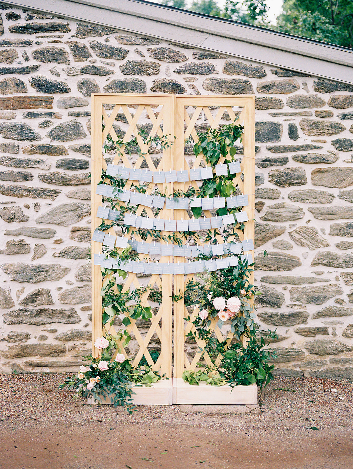 garden inspired place card display with fence and greenery in front of stone wall at Bartram's Garden wedding