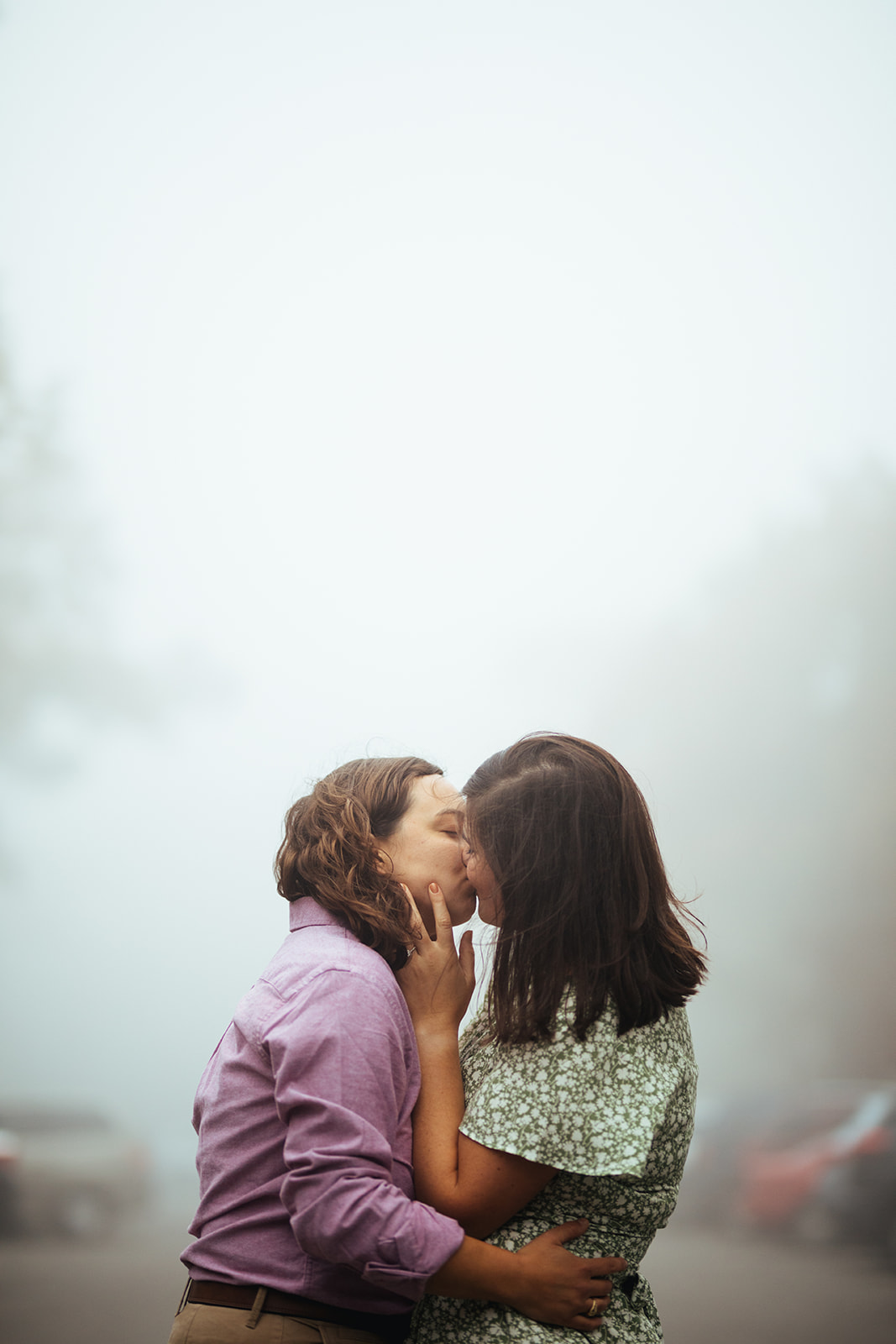 A queer couple kissing surrounded by dense fog at shenandoah national park. Dramatic engagement photo