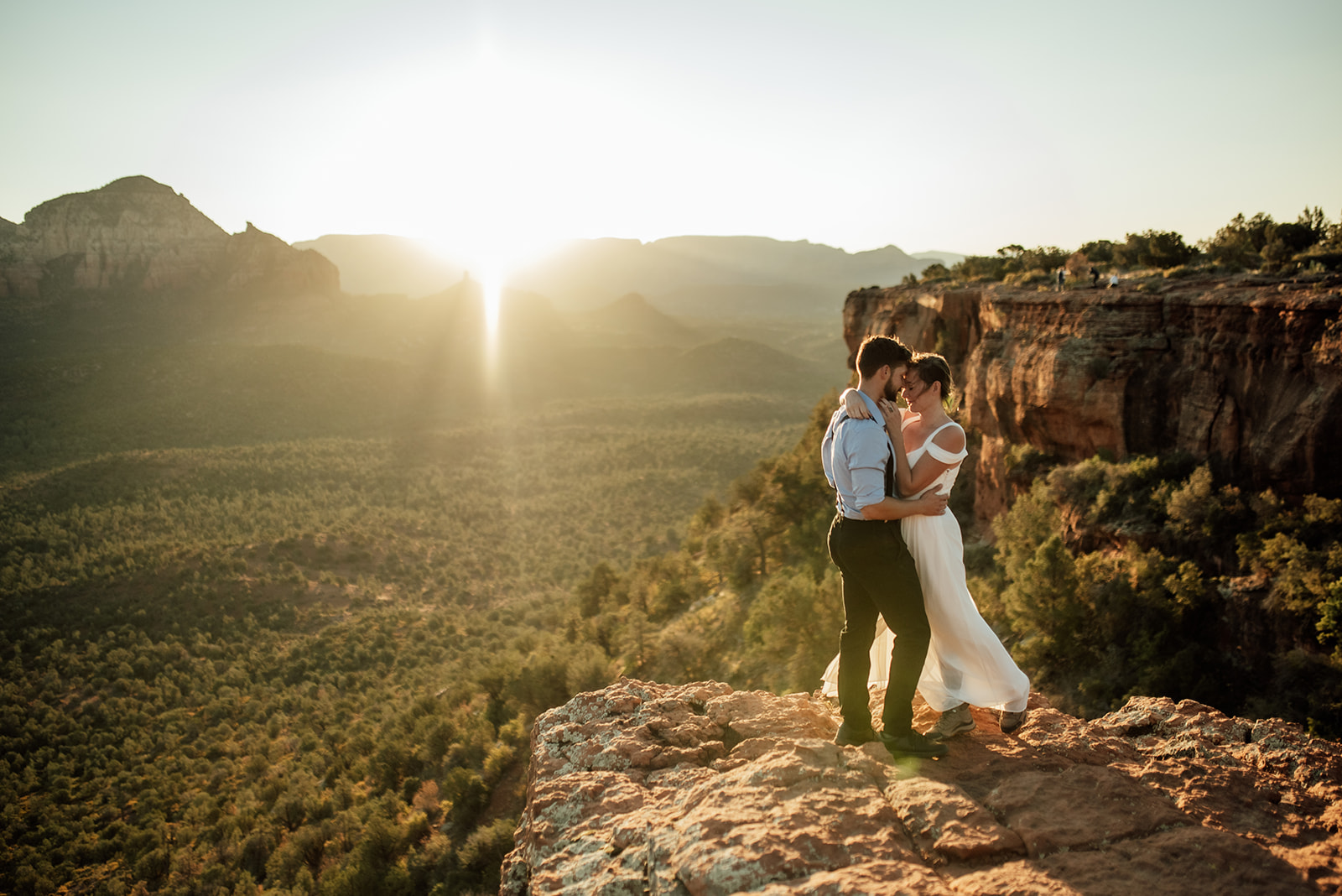 elopement couple on cliff with sunrise behind