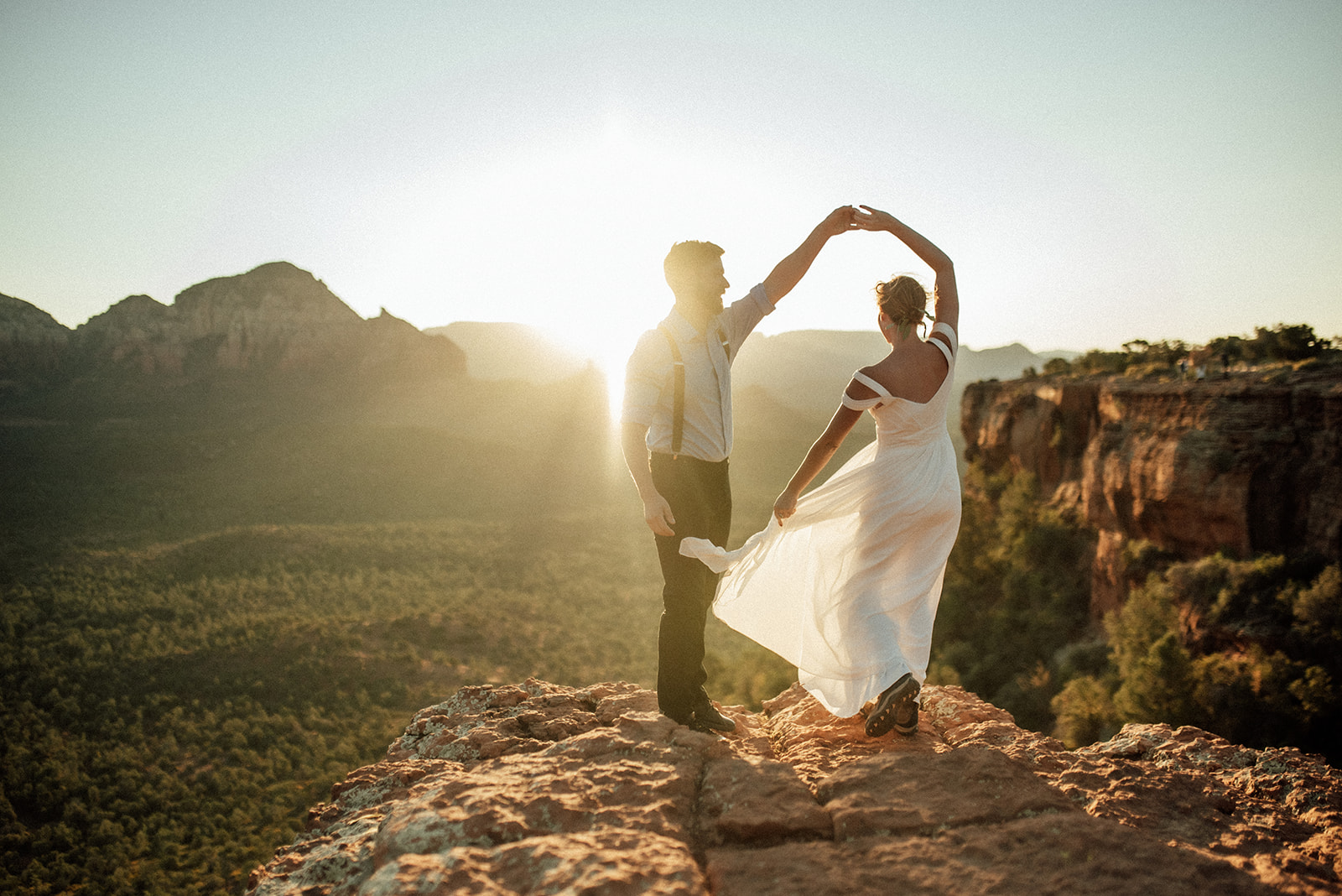 couple dancing on a cliff with sunrise behind