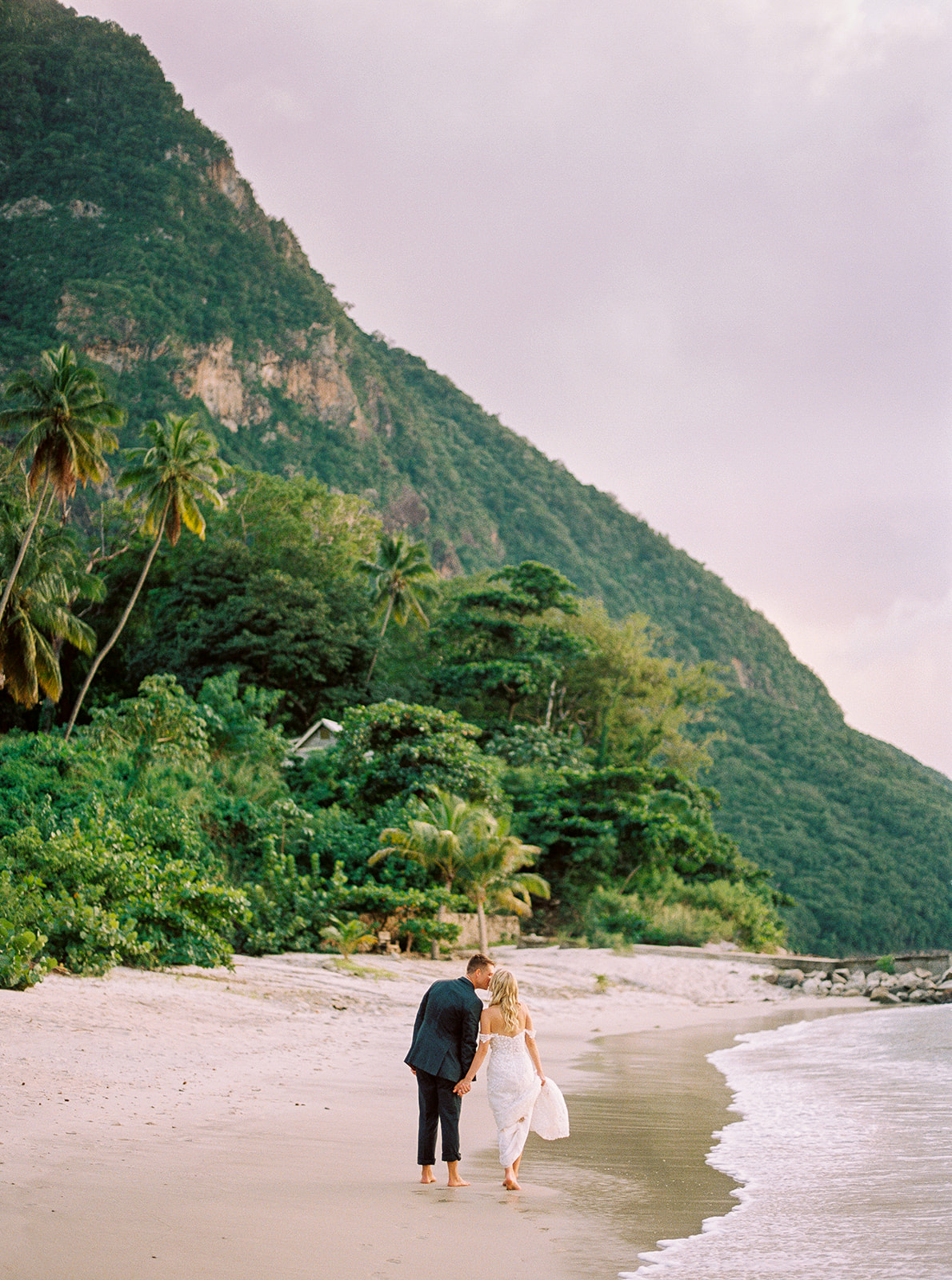 Bride and groom walk into the sunset with a view of the pitons at their Sugar Beach St Lucia wedding