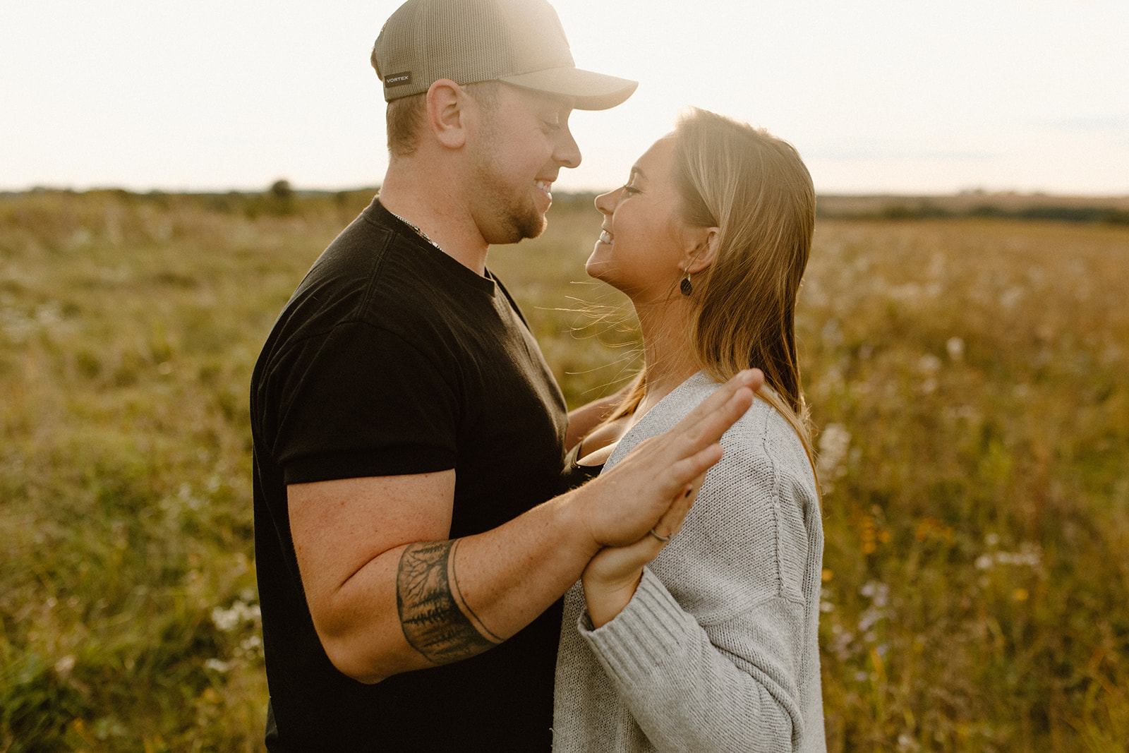 a couple in a grassy field at golden hour holding hands during a photo session