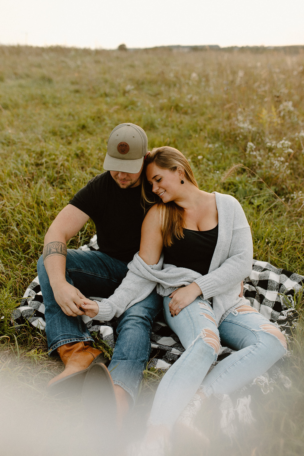 a couple sitting in a grassy field at golden hour during a photo session in barneveld, wisconsin 