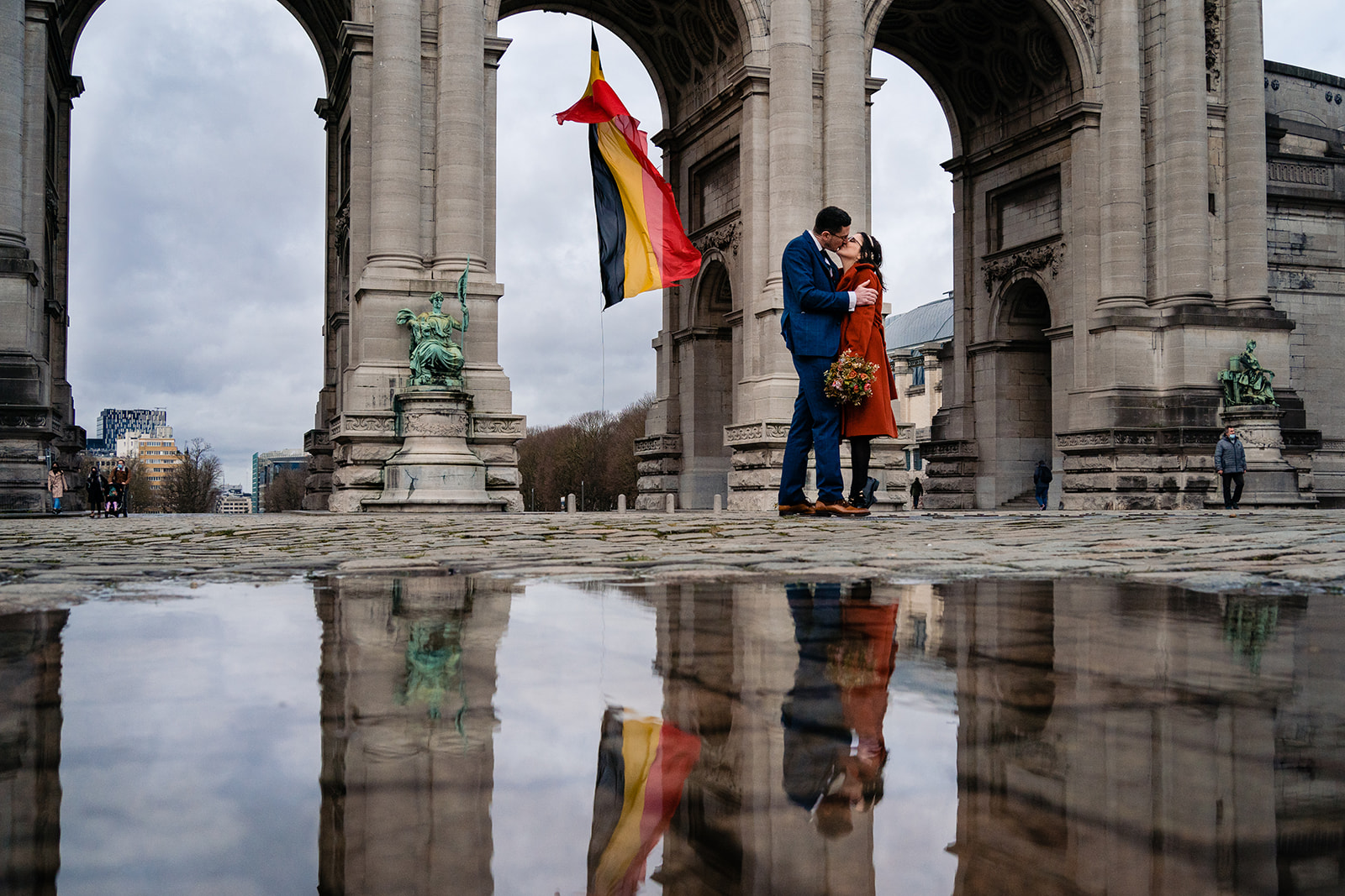 Reflet dans une flaque d'eau de mariés s'embrassant près des arches du cinquantenaire à Bruxelles après leurs mariage