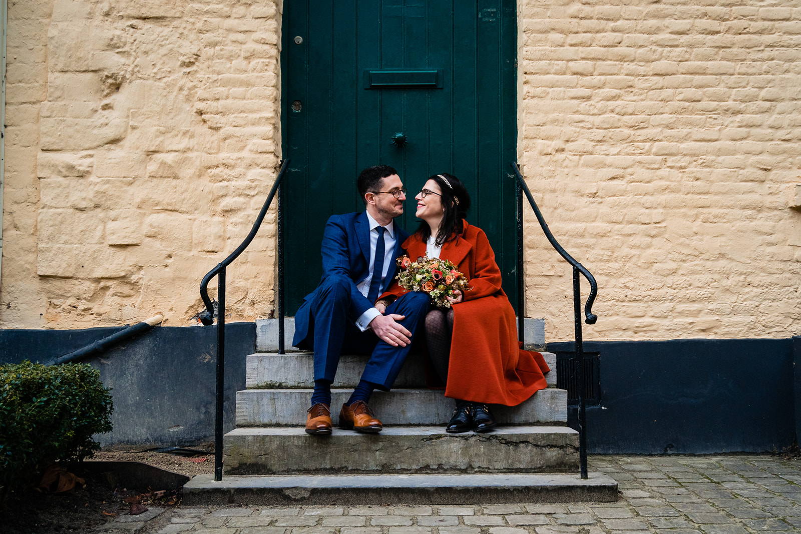 Un couple de jeune mariés assis sur des escaliers dans les jardins de l'abbaye de la Cambre à Bruxelles 
