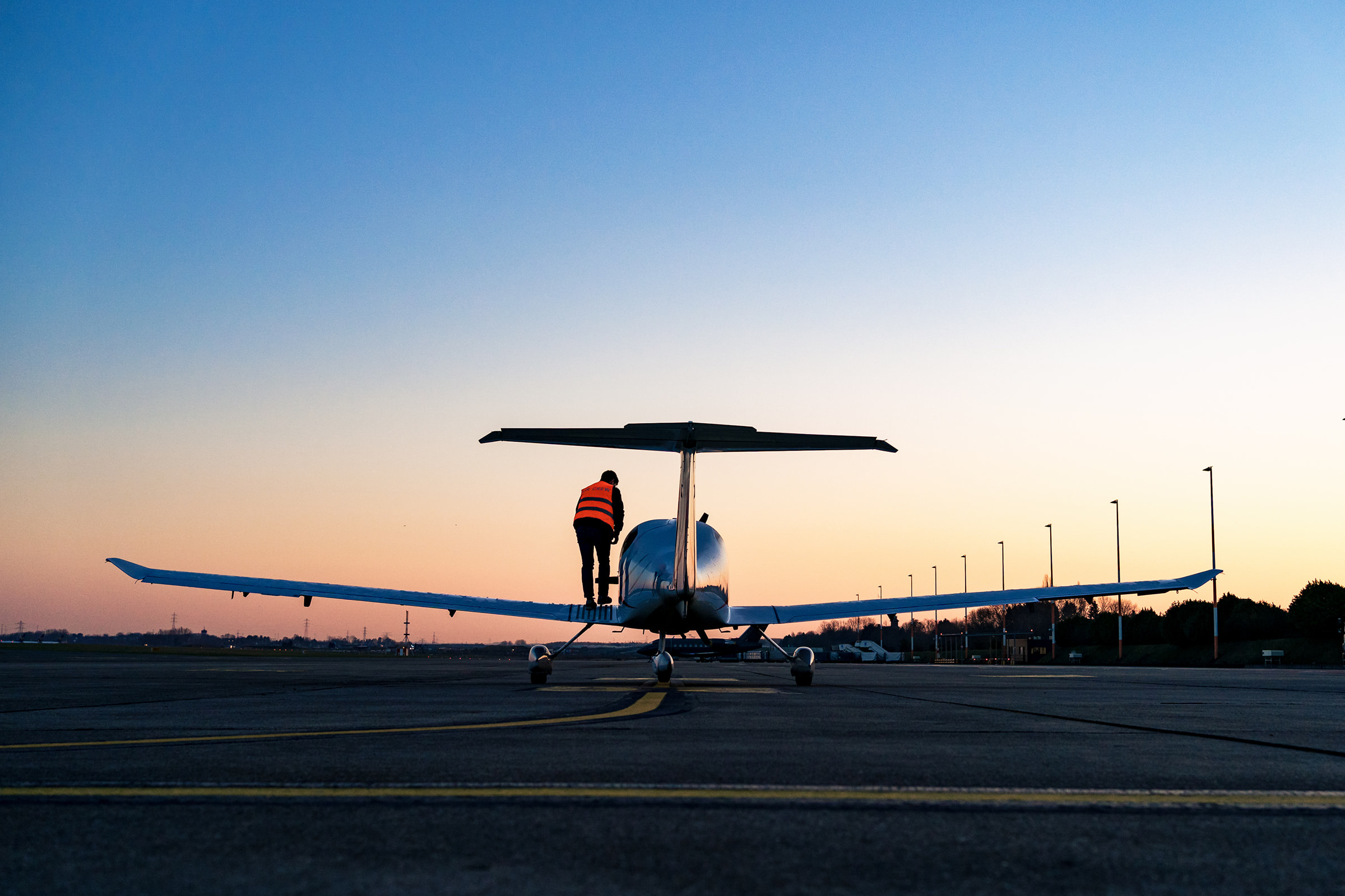 Silhouette d'un pilote sur l'aile d'un avion au sol lors du levé de soleil, fait par un photographe d'entreprise Brabant