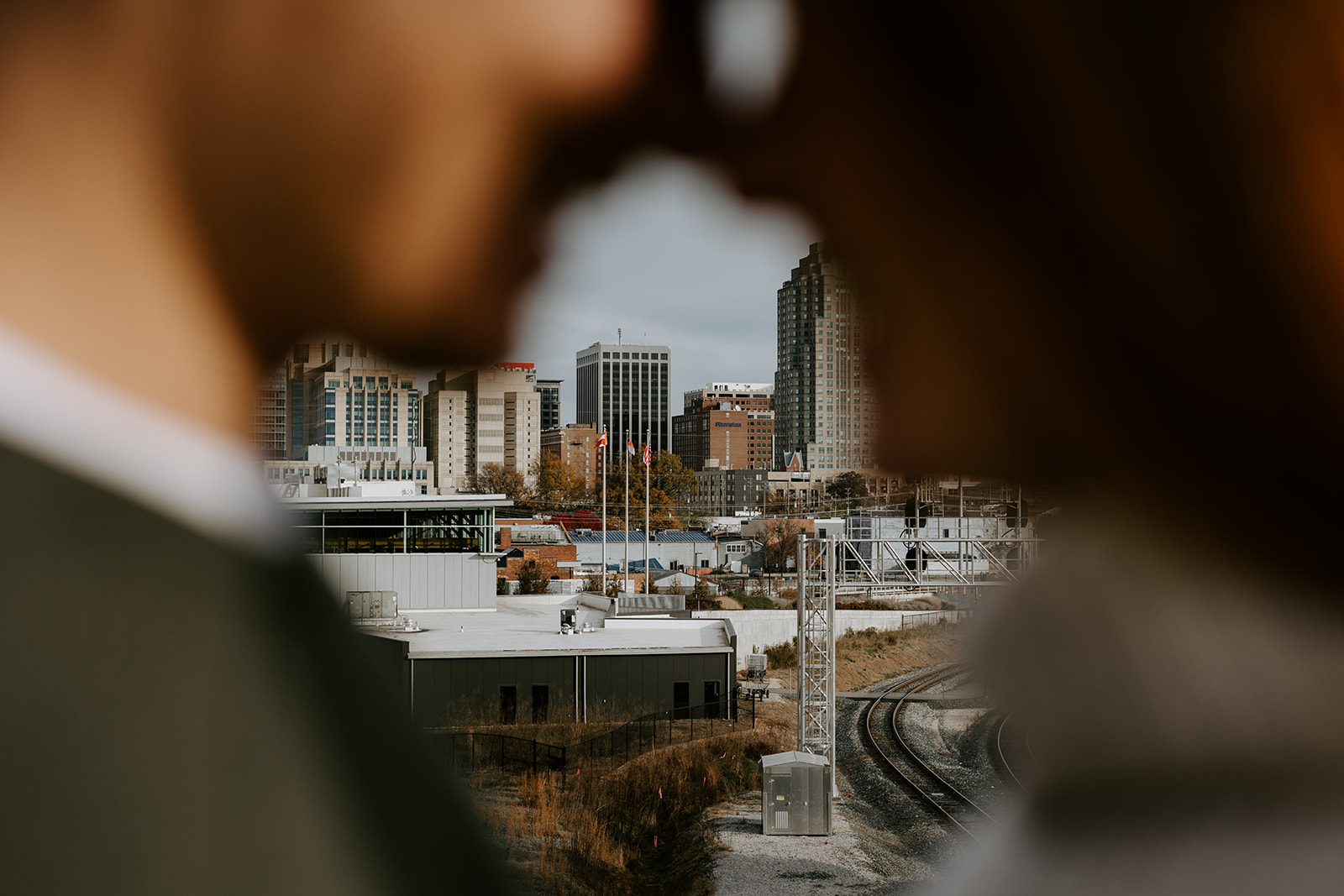 Engaged couple with city in the background on Boylan Bridge in Downtown Raleigh