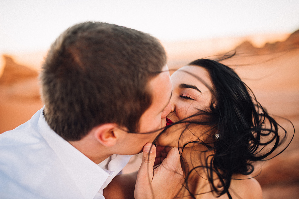 a couple shares a kiss in vibrant color, with her hair wildly dancing in the wind