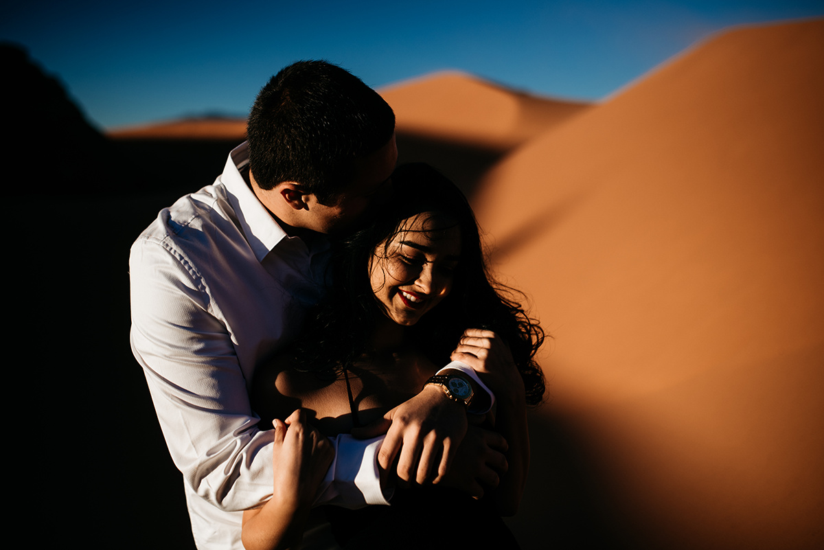 Couple shares a tender moment in the fiery Utah dunes, their love as timeless as the landscape