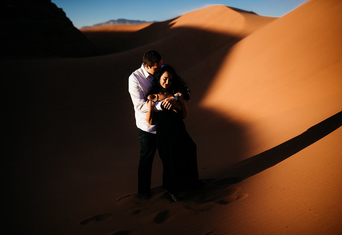 Couple sharing an emotive embrace in the fiery Utah dunes, their love as timeless as the landscape