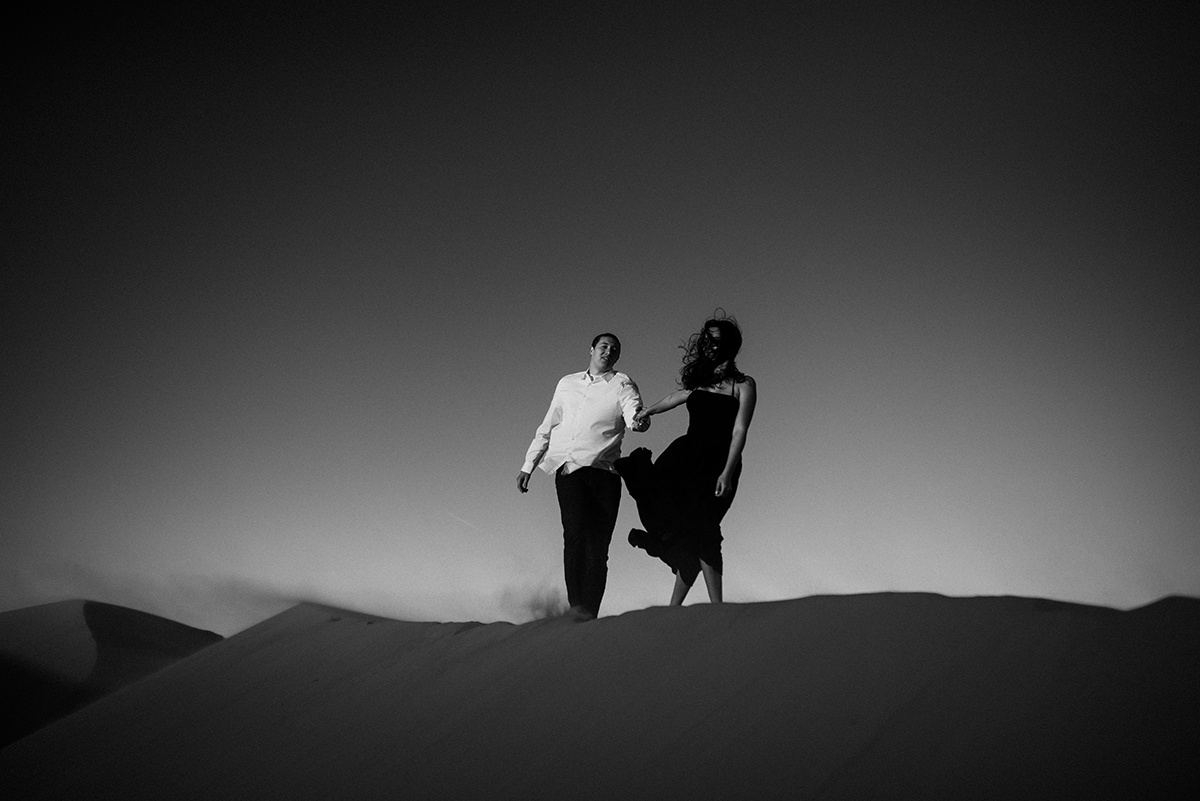 she leads him on a walk across the utah sand dune in a cinematic windswept moment