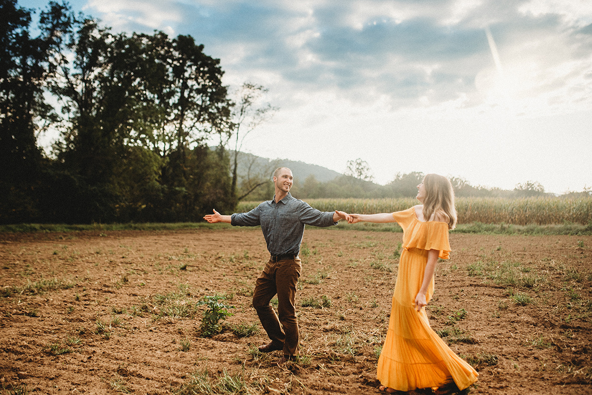 cinematic backlit edit of a husband leading his wife through  walking through a dirt field 