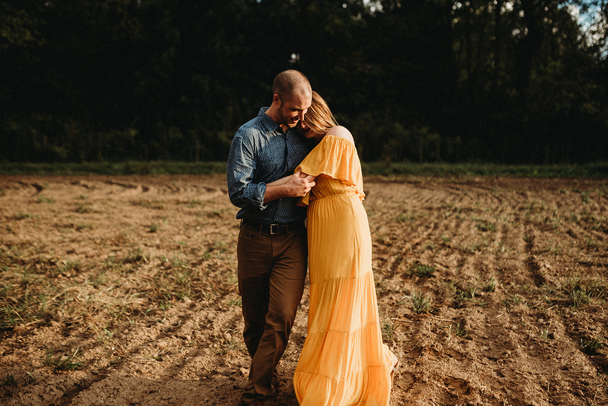 cinematic edit of a husband and wife holding onto one another while walking through a dirt field
