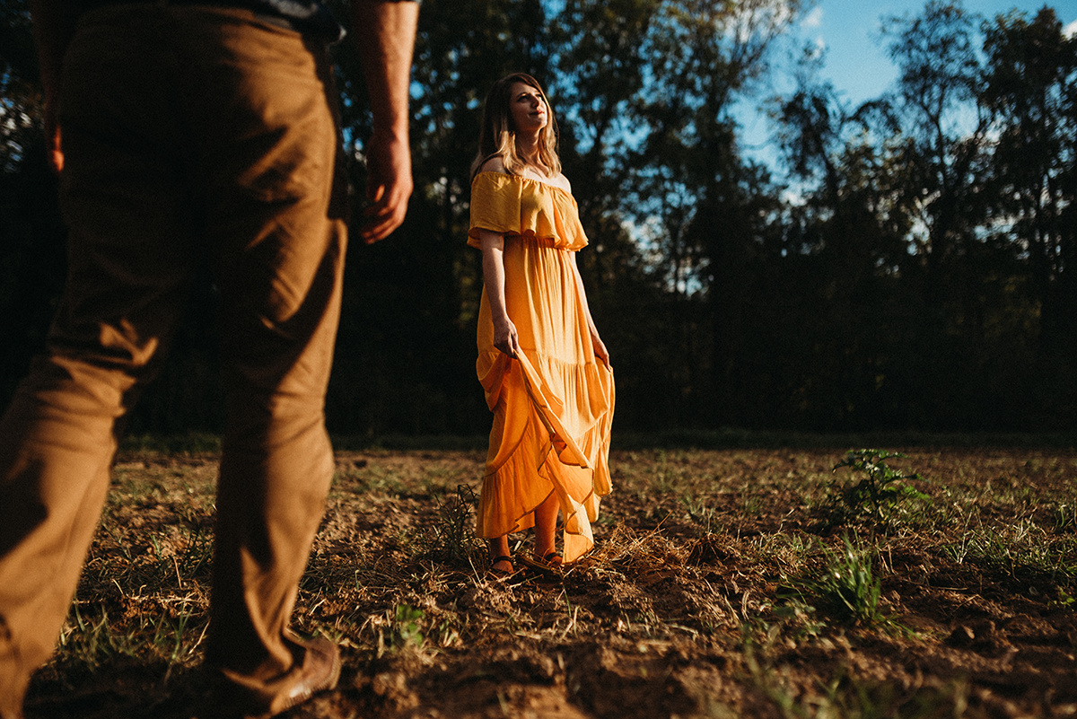 photo shot from a low perspective of a man walking towards a woman in a yellow dress basking in the direct sunlight