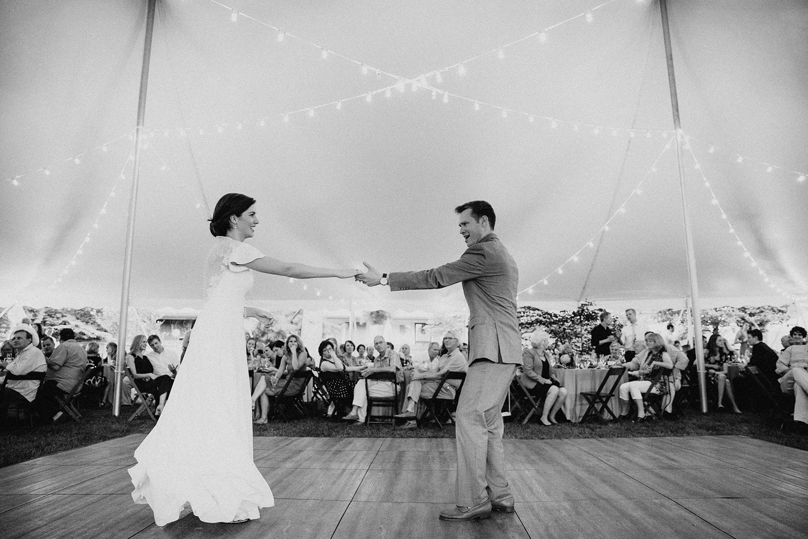 A bride and groom share their first dance under a tented wedding reception in the backyard of her childhood home