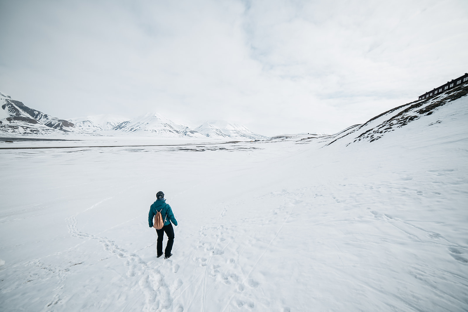 person standing in snow before snow covered mountain range on Svalbard
