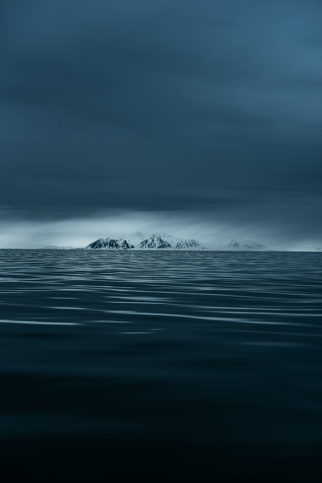 snow covered mountain range in the distance under a dark cloudy sky on Svalbard