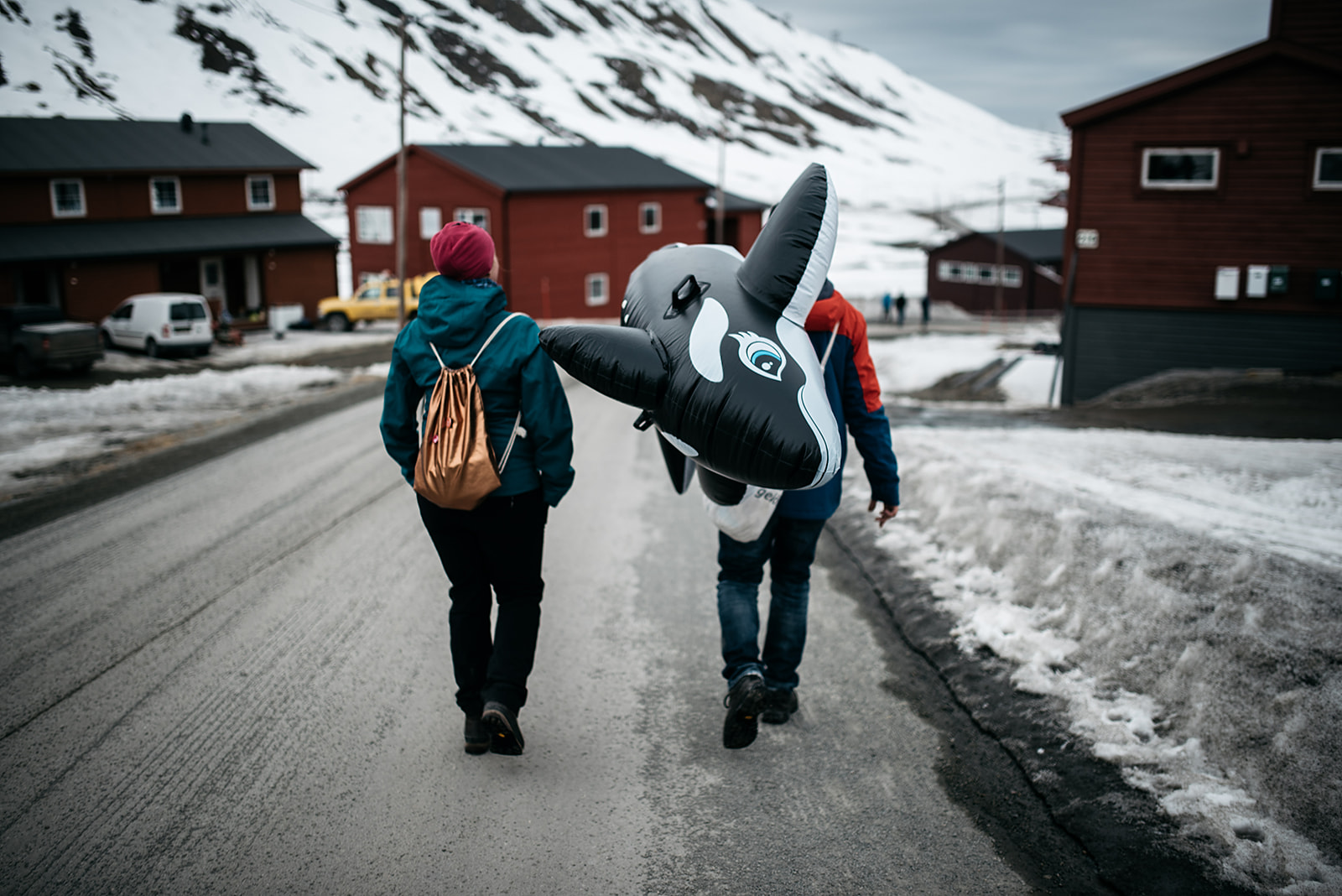 two people caring a toy orca through the city of Longyearbyen